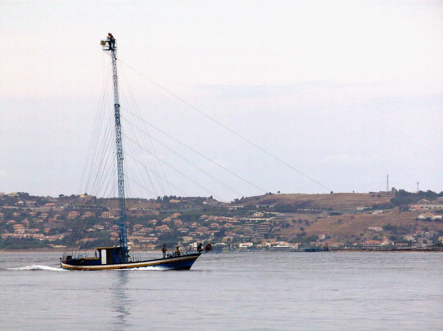 Fishing boat with tall mast in Cannitello, Italy
