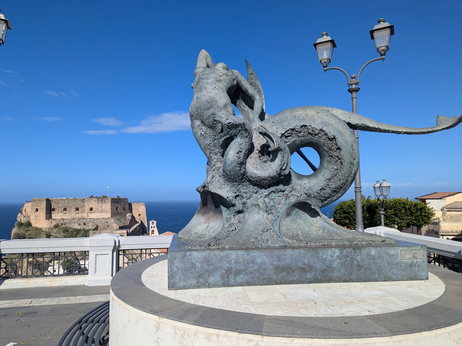 Sculpture of Scylla on Piazza San Rocco in Scilla with Ruffo Castle behind